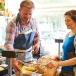 Sales Assistant Serving Female Customer At Checkout Of Organic Farm Shop
